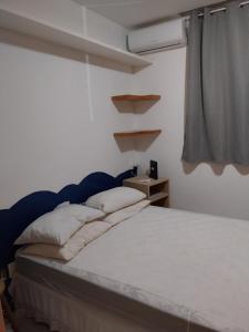 a bedroom with a bed with white sheets and a window at Casa em Village com piscina e perto da praia in Salvador