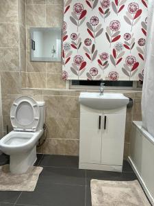 a bathroom with a white toilet and a sink at Modern 3 Bed House for 6 guests in Nevendon