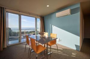 comedor con mesa y sillas y ventana grande en Waves on Esplanade - Kaikoura Waterfront Apartment, en Kaikoura