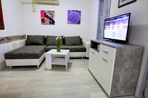a living room with a couch and a flat screen tv at Poolside compact family cottage Lea in Rovinjsko Selo