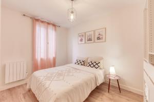 Joli appartement 8min de Paris! في روسني-سو-بوا: غرفة نوم بيضاء فيها سرير ومصباح