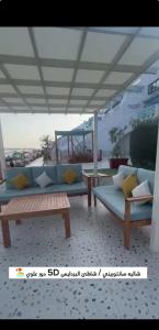 a patio with couches and tables on a beach at لافونتين بردايس in Durat  Alarous