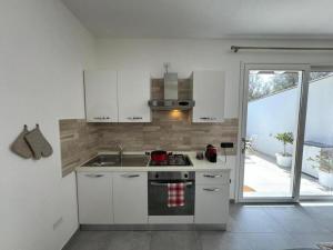 een keuken met witte kasten en een fornuis met oven bij Moderno e Confortevole Appartamento, Wi-Fi e Parcheggio Gratuito in Sanluri