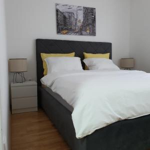 a bedroom with a large bed with white sheets and yellow pillows at JR Lux apartman in Stara Pazova