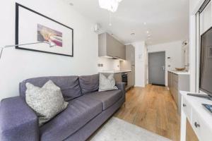 ein Wohnzimmer mit einem Sofa und einer Küche in der Unterkunft Modern Flat in Camden Town in London