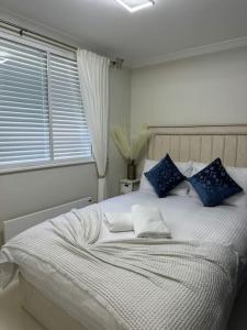 1 dormitorio con cama blanca y almohadas azules en 1 Bedroom Luxury Flat in Kensington, en Londres