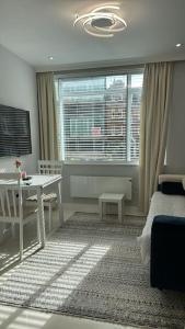 een woonkamer met een bed, een tafel en een raam bij 1 Bedroom Luxury Flat in Kensington in Londen