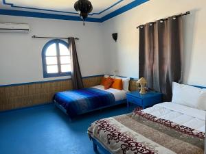 1 Schlafzimmer mit 2 Betten und einem Fenster in der Unterkunft ETOILE FILANTE D Or in Aït-Ben-Haddou