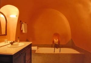a bathroom with a tub and a sink with two candles at Grand Canava in Oia