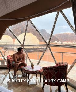 a man sitting in a chair in front of a window at Rum city Star LUXURY Camp in Wadi Rum