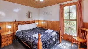 a bedroom with a bed and a chair and windows at Crayfish Creek Van & Cabin Park in Crayfish Creek