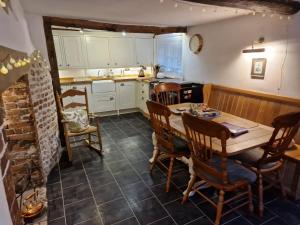 a kitchen with a table and chairs and a kitchen with white cabinets at Delightful 3bed thatched Cottage in Stockbridge