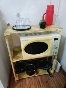 un four micro-ondes sur une étagère avec des casseroles et des poêles dans l'établissement Studio Prime - Niterói 704, à Niterói