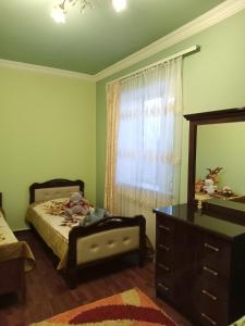 a bedroom with a bed and a dresser and a window at Family house in Sevan