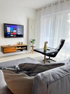 a living room with a couch and a table and a tv at Living at Saarpartments with 2 Bedrooms, Netflix- Business & Holiday Apartments for Long- and Short term Stay, 3 min to Train-Station and Europa Galerie in Saarbrücken
