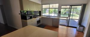 a kitchen with white cabinets and a large window at Beachcomber - 39 Phillip Drive South West Rocks in South West Rocks