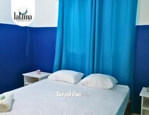 uma cama com duas almofadas em frente a uma cortina azul em Bayahibe Village Inn em Bayahibe
