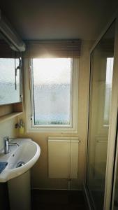 a bathroom with a sink and a window at Cozy Private Static Caravan at Llyons Robin Hood - Silver Birch Way 11 in Rhyl