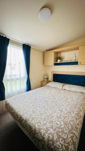 a bedroom with a large bed and a window at Cozy Private Static Caravan at Llyons Robin Hood - Silver Birch Way 11 in Rhyl