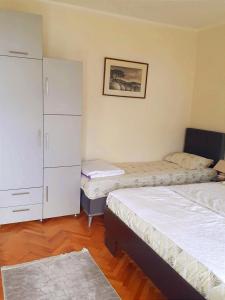 a bedroom with two beds and a cabinet at Guesthouse Gavrilović 28 A in Njivice