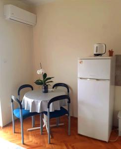 a table with two chairs and a white refrigerator at Guesthouse Gavrilović 28 A in Njivice