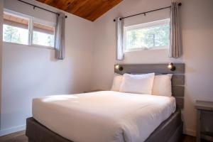a bedroom with a large white bed with two windows at Manning Park Resort in Manning Park