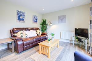 a living room with a brown leather couch and a tv at Spacious & Modern 2 Bed sleeps 5 in Walthamstow in London