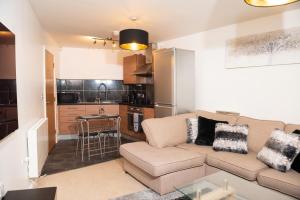 a living room with a couch and a kitchen at Spacious 2 bedroom Flat opposite COOP Live n Etihad Stadium in Manchester