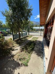 a sidewalk next to a building with a tree and a fence at Casa Tilo in El Bolsón