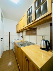 a kitchen with wooden cabinets and a tea kettle on a counter at Apartman Klara 102 in Mostar +4 photos