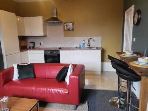 a living room with a red couch in a kitchen at Nice 2 bedroom (3 beds) house in Huddersfield in Lindley