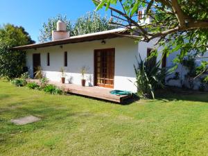 ein kleines weißes Haus mit einer Holzterrasse in der Unterkunft Arena&Mar in San Clemente del Tuyú + 14 Fotos