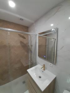 a bathroom with a sink and a shower with a mirror at Caparica Apartment near beach in Costa da Caparica