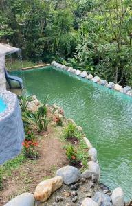 een zwembad van water met rotsen en bloemen in een tuin bij El Edén; Un paraíso irresistible. in Barbosa