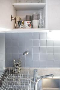 a kitchen with a sink and a shelf with cups at En famille ou entre amis in Mondelange