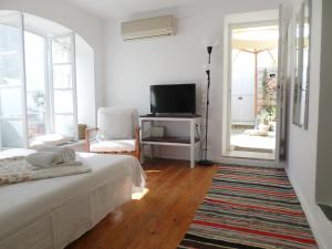a white bedroom with a bed and a television at In the heart of Hydra in Hydra