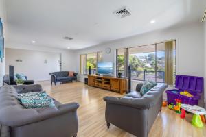 een woonkamer met 2 banken en een flatscreen-tv bij Kallaroo great house with views pool WI FI and aircon in Corlette