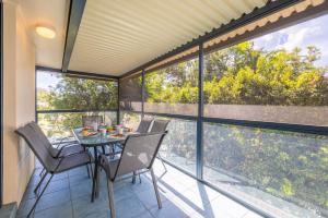 een eetkamer met een tafel en stoelen op een balkon bij Kallaroo great house with views pool WI FI and aircon in Corlette