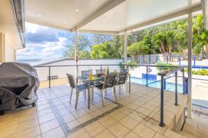 een patio met een tafel en stoelen en een zwembad bij Kallaroo great house with views pool WI FI and aircon in Corlette
