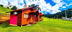 a small house in a field with a church in the background at Cabanas Tia Zizi in Urubici