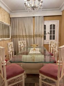 uma sala de jantar com uma mesa de vidro e um lustre em Lovely apartment 2 em Alexandria