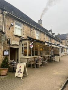 Priory Tearooms Burford with Rooms في بورفورد: مطعم فيه طاولات وكراسي امام مبنى