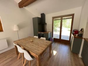 a kitchen with a wooden table and white chairs at Maisonnette dans la vallée verte in Fillinges