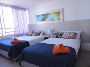 a bedroom with two beds with orange towels on them at Apartamento Mares de Cartagena in Cartagena de Indias +15 photos