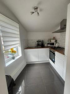 eine Küche mit weißen Schränken und einem Fenster in der Unterkunft EEJs Modern 3 bed flat near Crystal Palace Stadium with great transport links in Norwood
