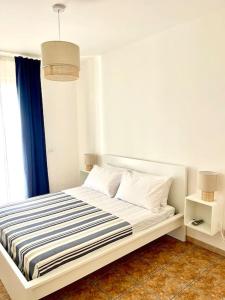 a bedroom with a white bed with a blue curtain at Casa Vacanze La Baia in Messina