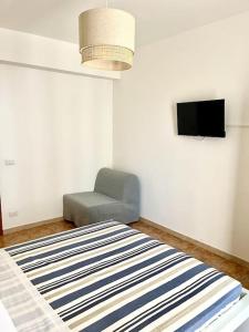 a room with a bed and a chair and a television at Casa Vacanze La Baia in Messina