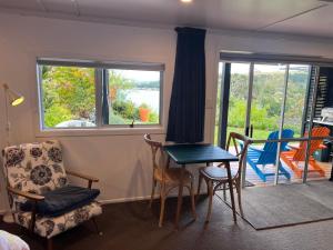 sala de estar con mesa, sillas y ventana en Brophys Beach Studio, en Whitianga