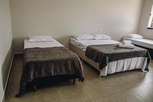 duas camas num pequeno quarto com saias em Pousada Casa Vista Bela São José da Barra Capitólio em São José da Barra