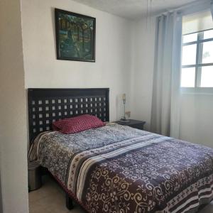 ein Schlafzimmer mit einem Bett mit einer Decke und einem Fenster in der Unterkunft Acapulco Diamante in Acapulco